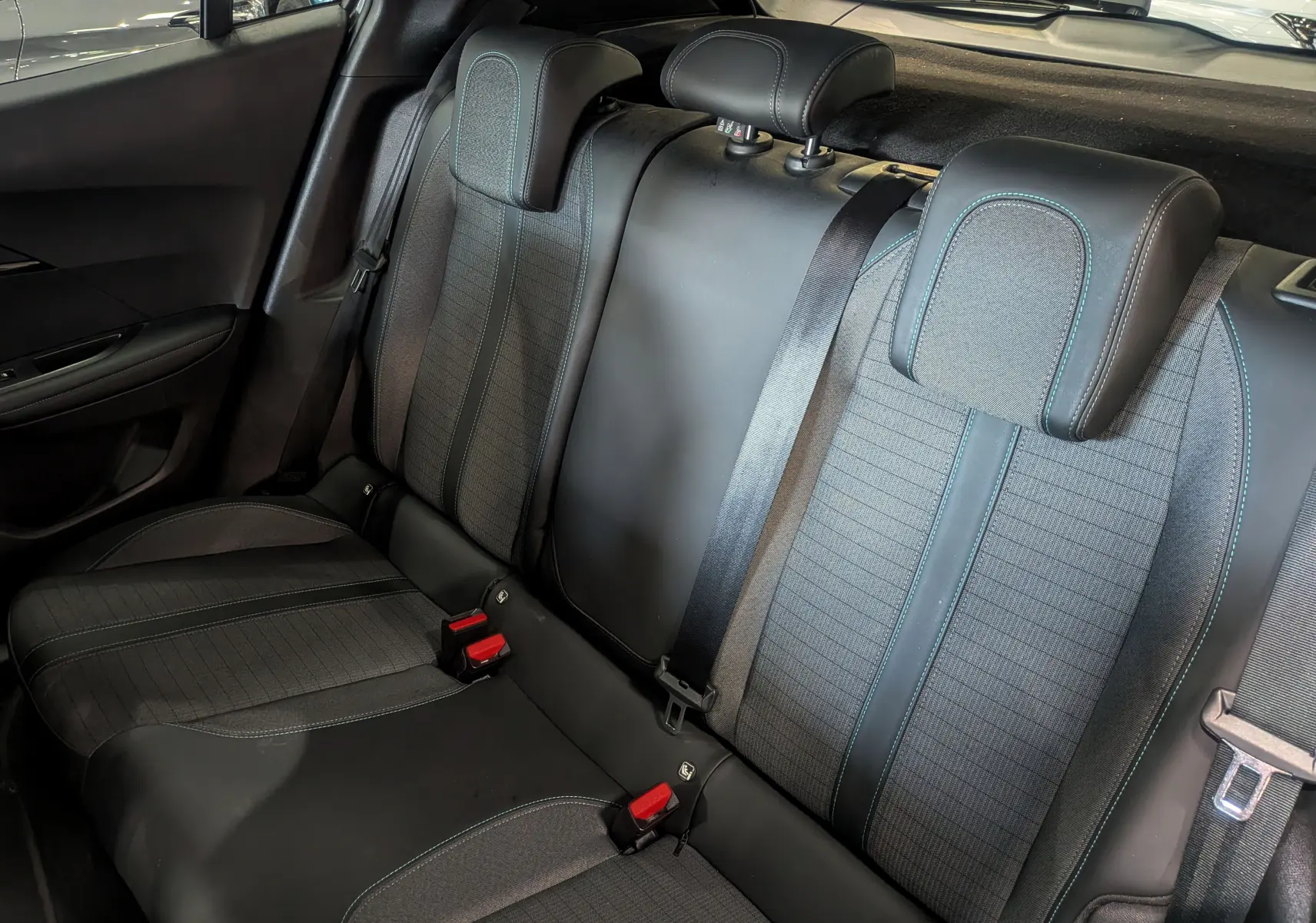 Vue intérieure des sièges arrière en tissu noir avec surpiqûres bleues du Peugeot 2008 PureTech 100 Allure 2021.
