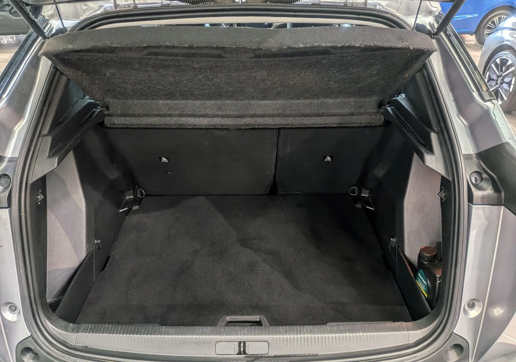 Coffre ouvert vu de l'arrière d'un Peugeot 2008 Gris Artense, montrant un espace de chargement propre et vide.
