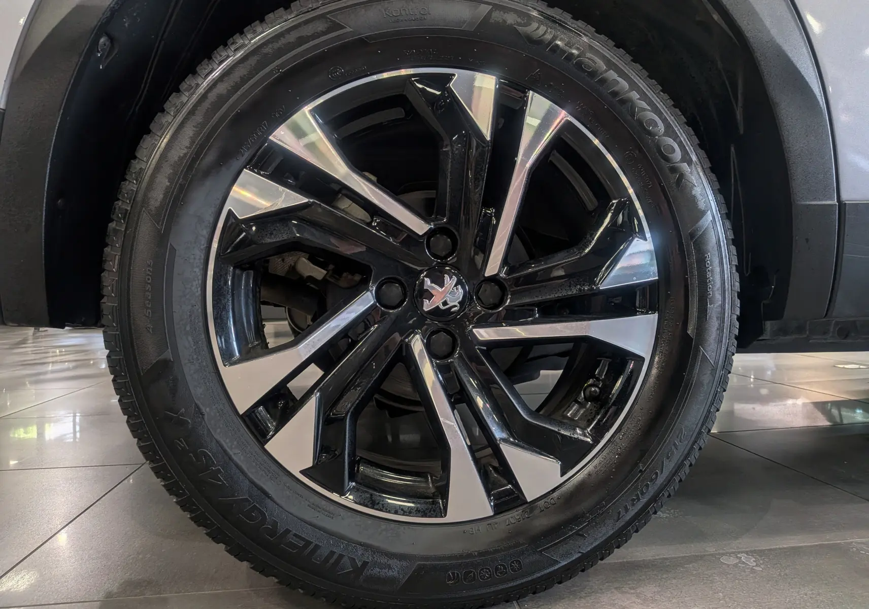 Gros plan sur la jante biton noir et argent d’un Peugeot 2008 Gris Artense, vue côté roue avant droite.