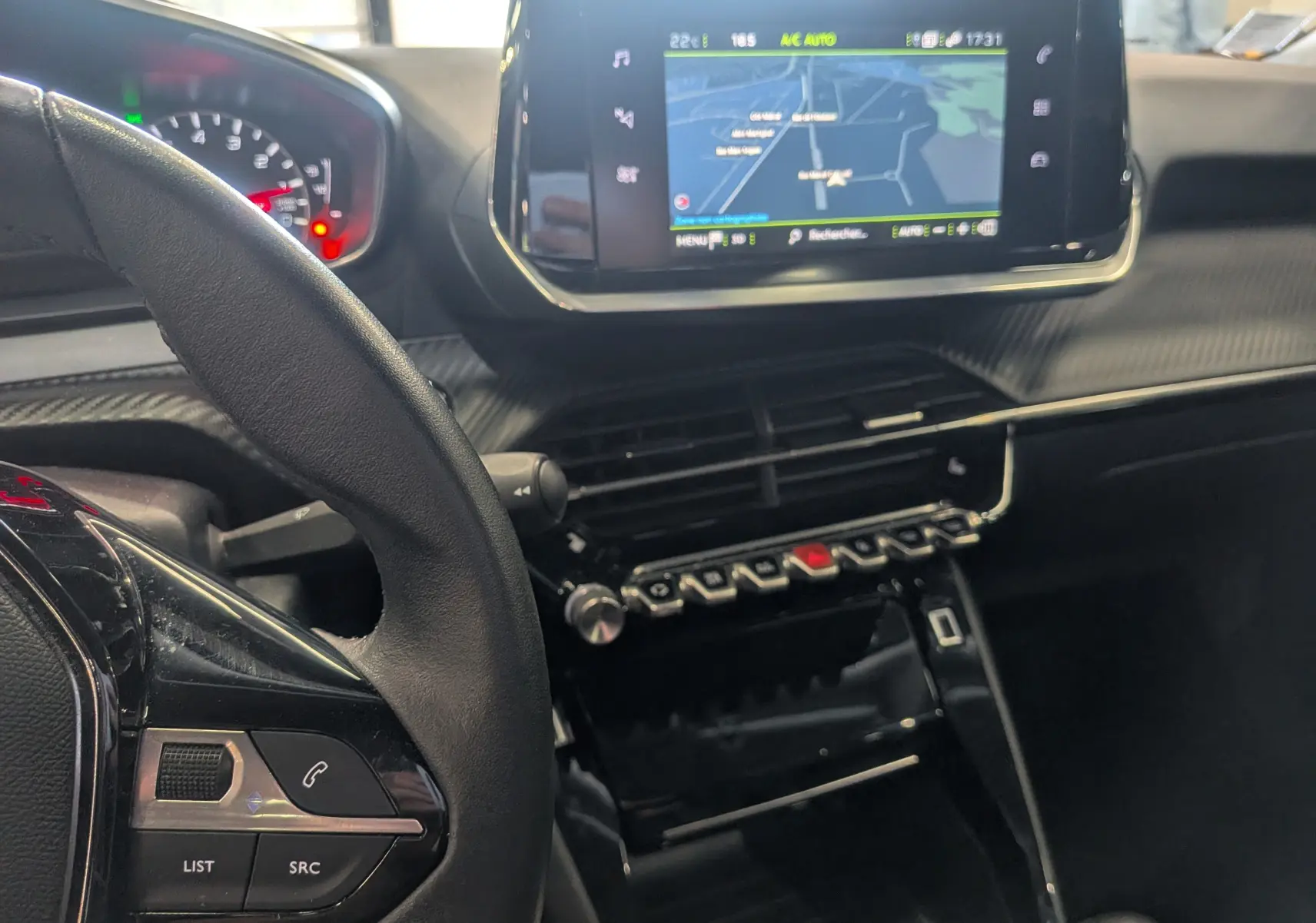 Vue intérieure du tableau de bord et volant côté gauche du Peugeot 2008 gris Artense avec écran tactile et commandes intégrées.