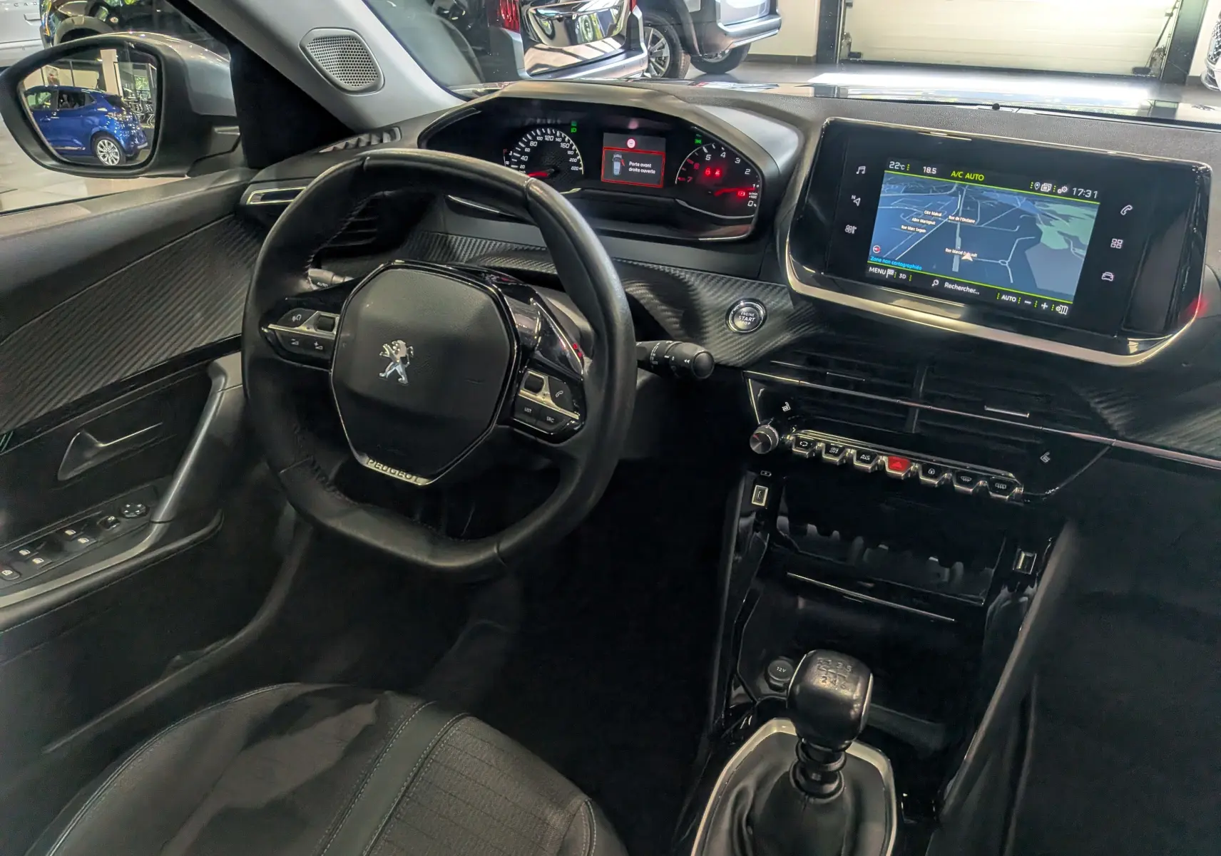 Vue intérieure côté conducteur du Peugeot 2008 gris Artense, avec volant compact, tableau de bord numérique et écran tactile central.