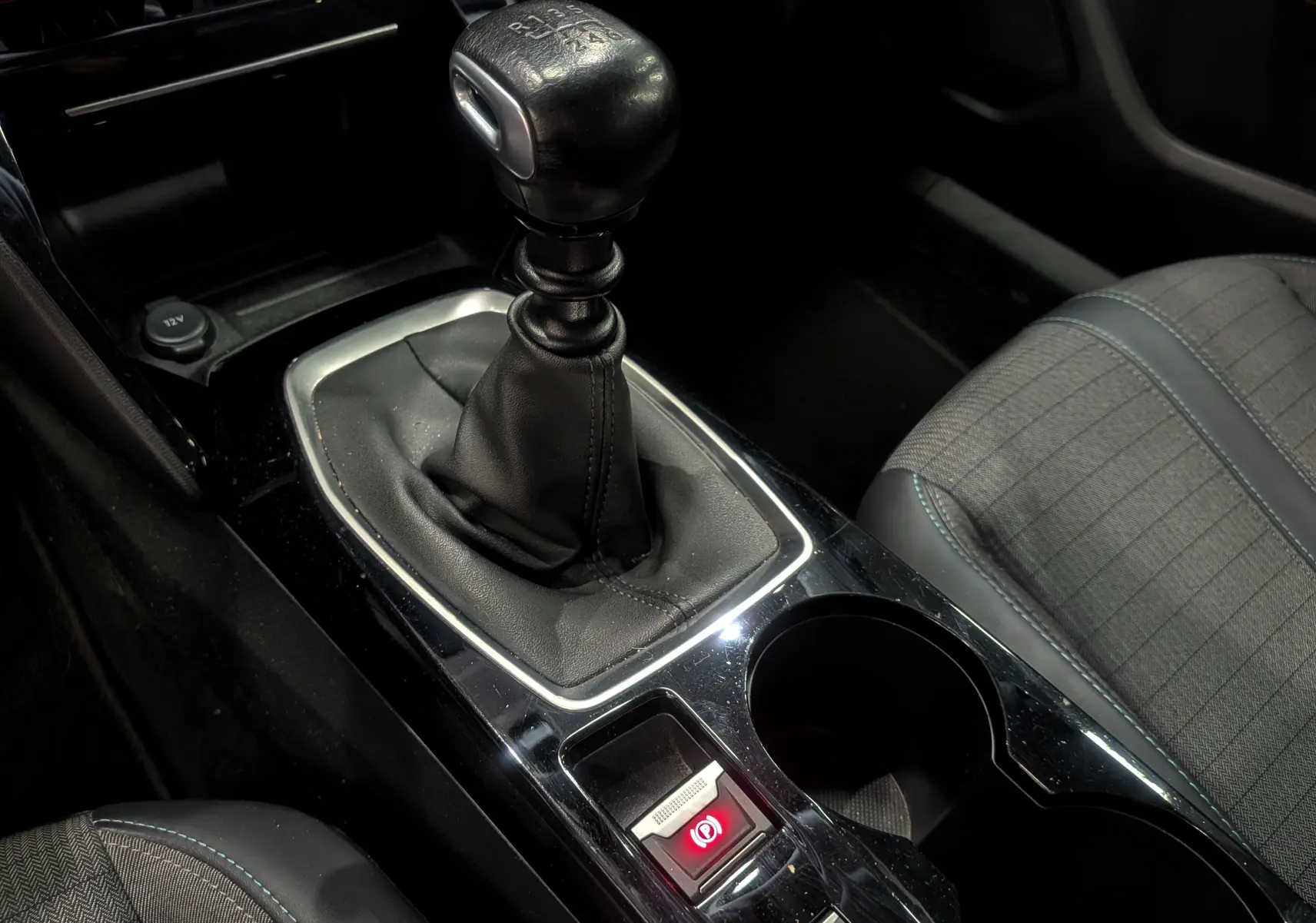 Gros plan sur le levier de vitesse manuel noir et la console centrale du Peugeot 2008 gris Artense, avec siège tissu visible.