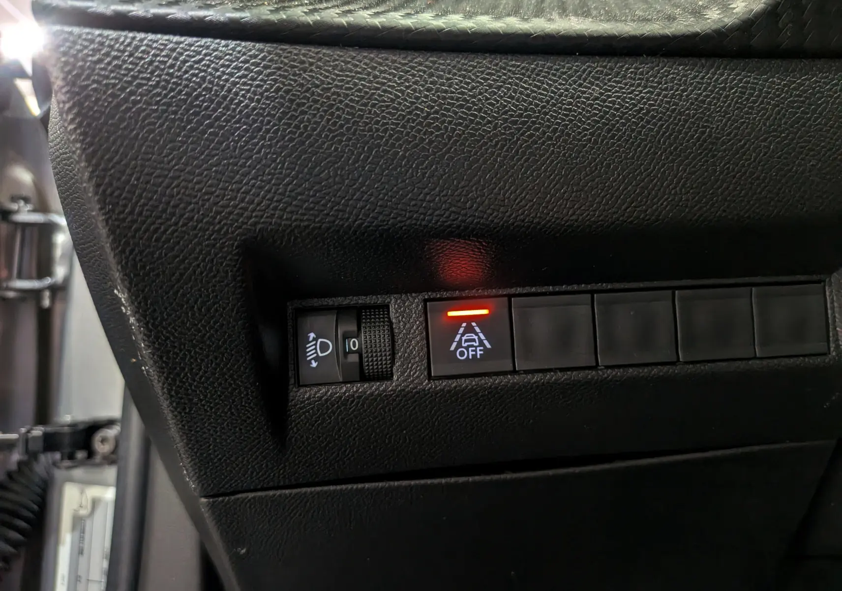 Détail du tableau de bord noir du Peugeot 2008 PureTech 100 Allure 2021 avec bouton d'alerte de maintien de voie désactivé.