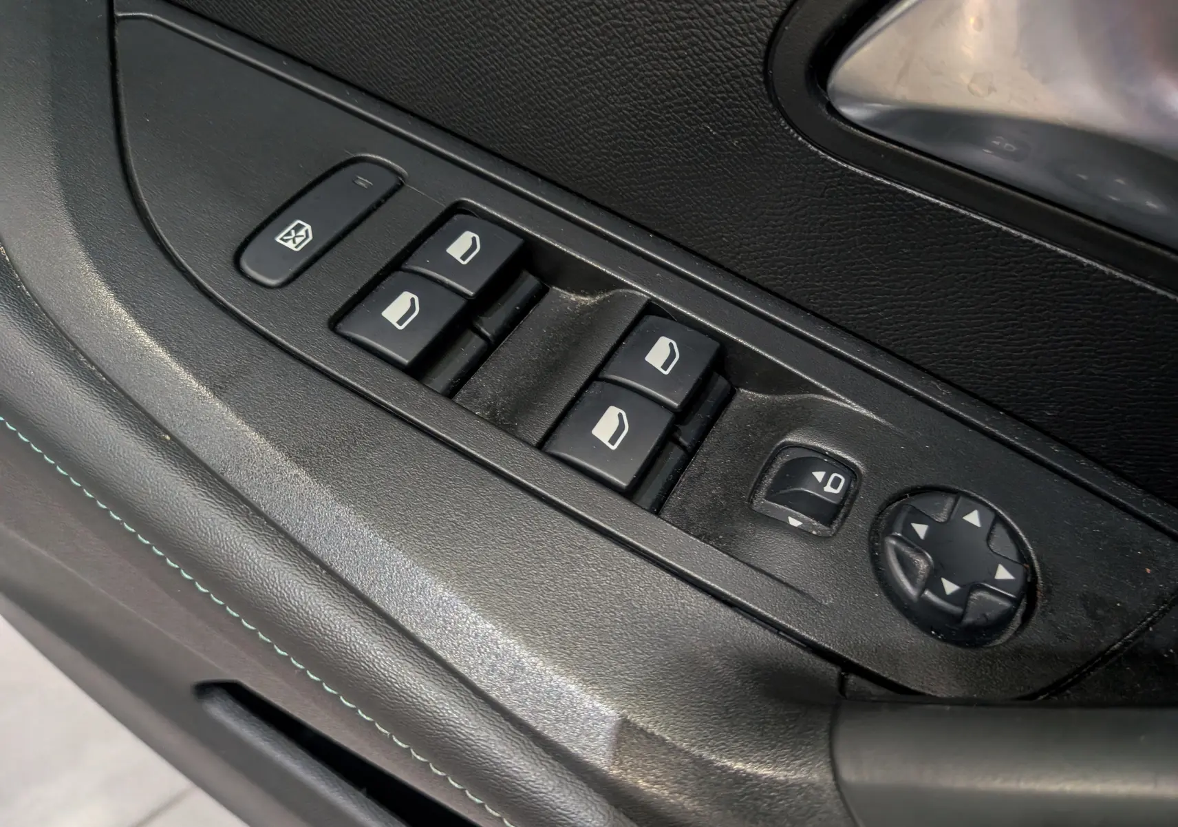 Gros plan sur les commandes de lève-vitres et réglage des rétroviseurs côté conducteur d’un Peugeot 2008 Gris Artense.