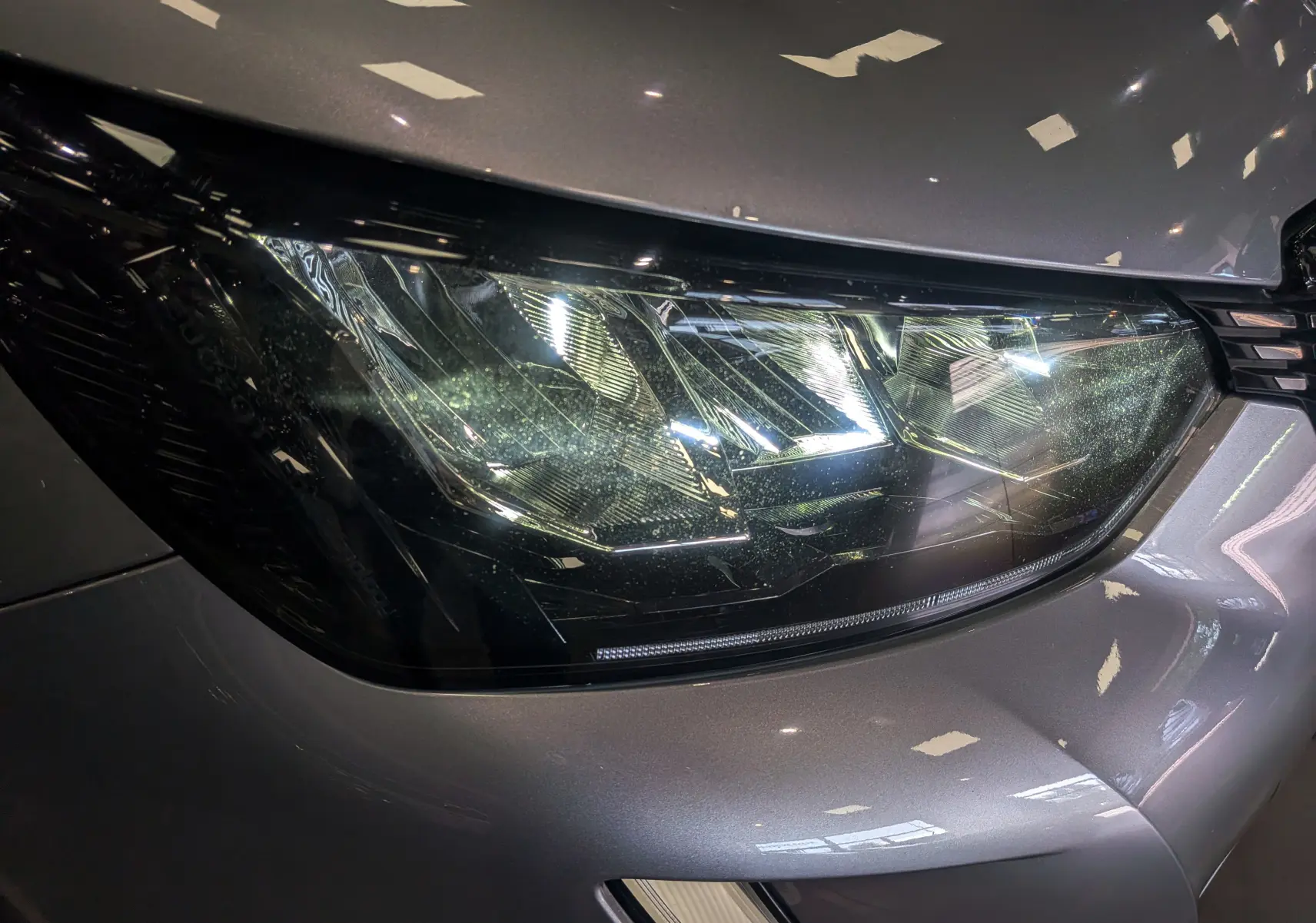 Gros plan sur le phare avant droit gris Artense du Peugeot 2008 PureTech 100 Allure 2021, détails lumineux visibles.