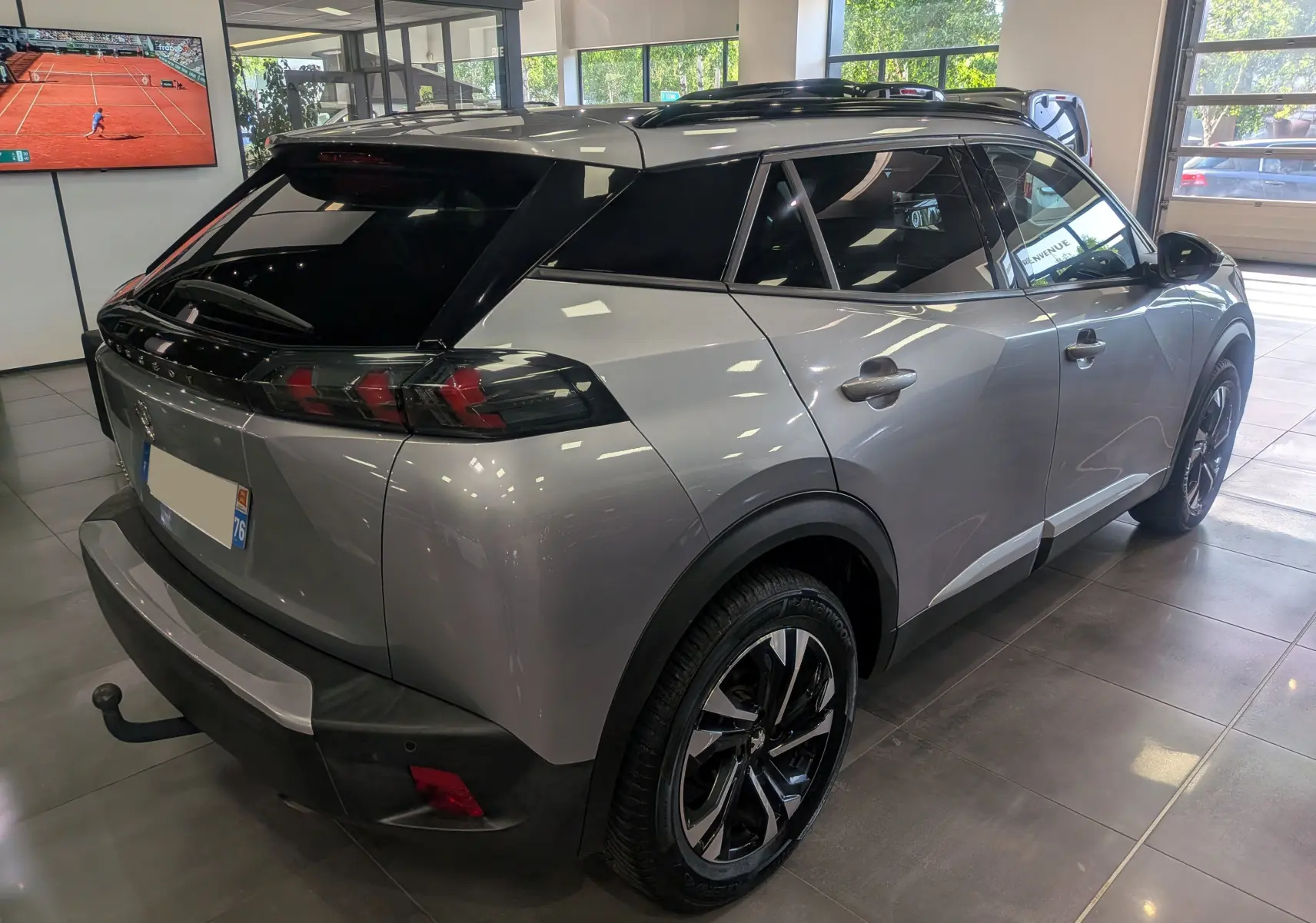 Peugeot 2008 gris Artense vue 3/4 arrière droit en intérieur, avec toit noir et jantes bi-ton distinctives.
