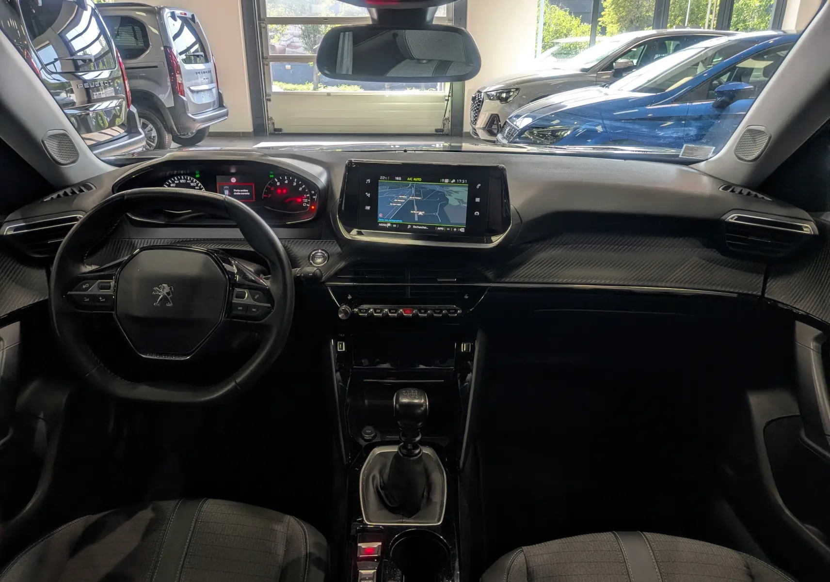 Vue intérieure frontale du tableau de bord du Peugeot 2008 gris Artense avec écran tactile et volant compact multifonction.