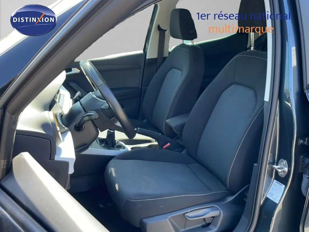 Vue intérieure côté conducteur du SEAT Arona gris Magnetic Metal, montrant les sièges tissu gris et la console centrale.