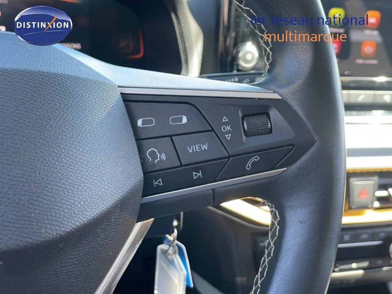 Gros plan sur le volant cuir noir du SEAT Arona 2025, avec commandes intégrées et tableau de bord en arrière-plan.