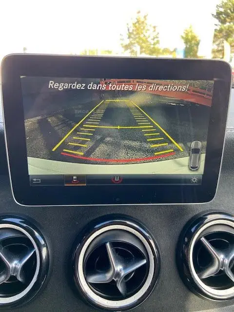 Écran de caméra de recul dans une Mercedes CLA Shooting Brake 200D WhiteArt Edition, affichant les lignes de guidage jaunes et rouges.