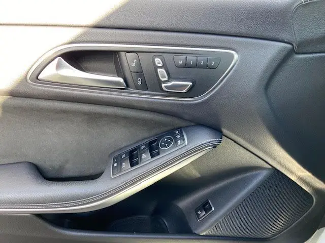 Détail de la porte côté conducteur de la Mercedes Classe CLA Shooting Brake 200D WhiteArt Edition avec commandes de siège et vitres en cuir noir.