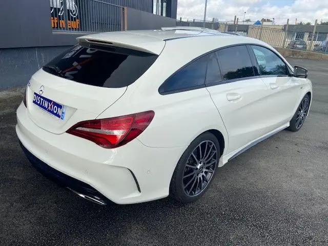 Vue 3/4 arrière droite d'une Mercedes CLA Shooting Brake 200D WhiteArt blanche avec jantes AMG noires et vitres teintées.