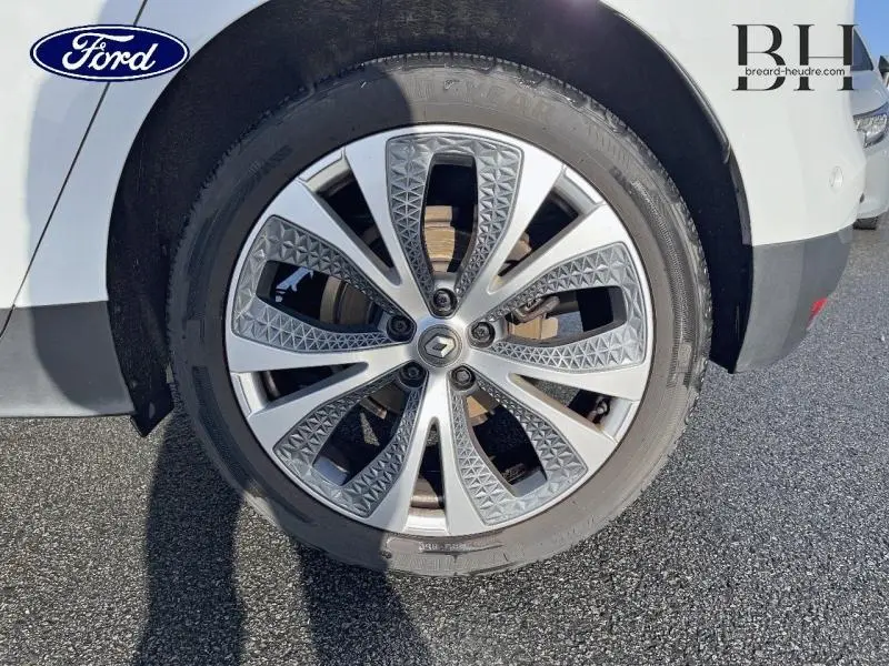 Gros plan sur la roue avant gauche du Renault Scénic blanc nacré avec jante alliage au design géométrique.