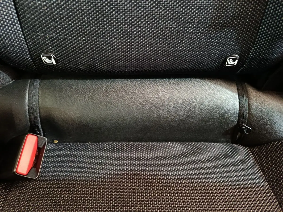 Gros plan sur la banquette arrière noire du Renault Captur 2024, montrant les fixations Isofix et la boucle de ceinture rouge.