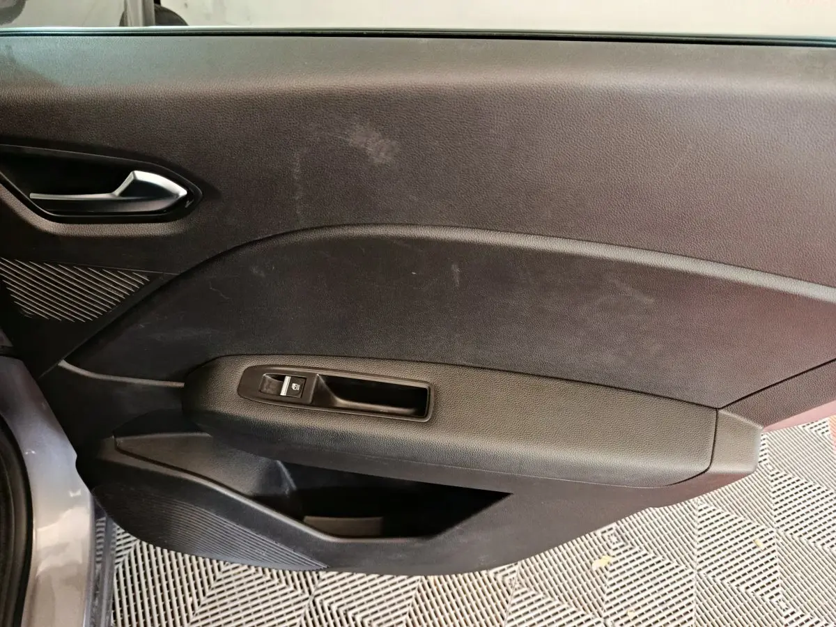Vue rapprochée de la porte intérieure côté gauche du Renault Captur gris foncé, montrant la poignée et le bouton de vitre électrique.