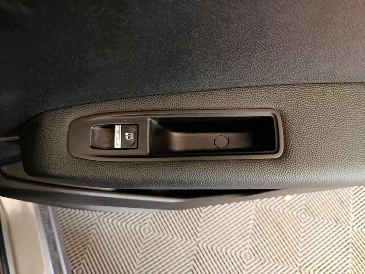 Gros plan sur la commande de lève-vitre côté gauche de la porte d’une Renault Captur gris foncé 2024.