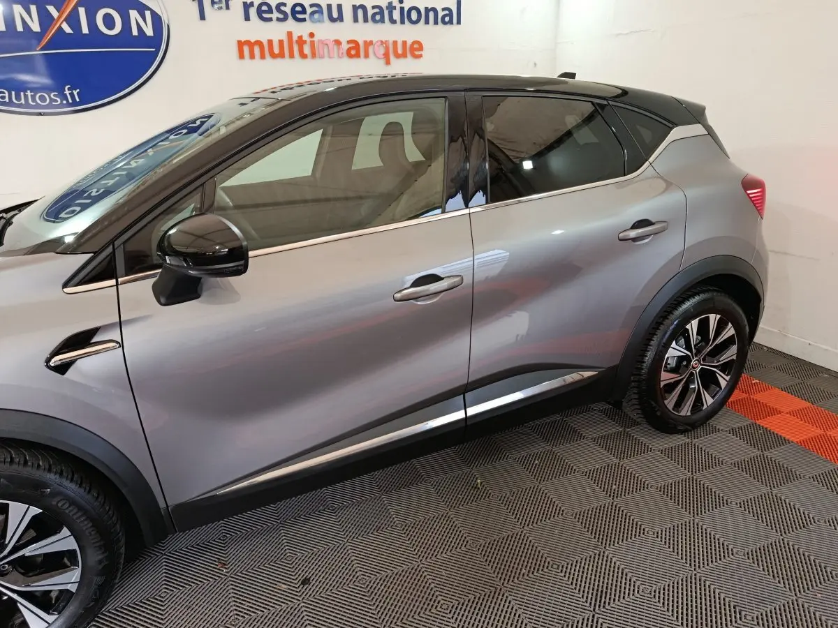 Vue latérale droite d’un Renault Captur 2024 gris foncé avec toit noir et jantes alliage bicolores.