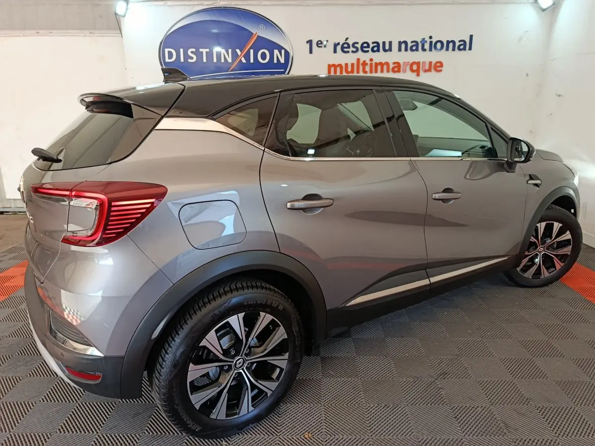 Vue 3/4 arrière droite d’un Renault Captur 2024 gris foncé avec jantes alliage et toit noir contrasté.