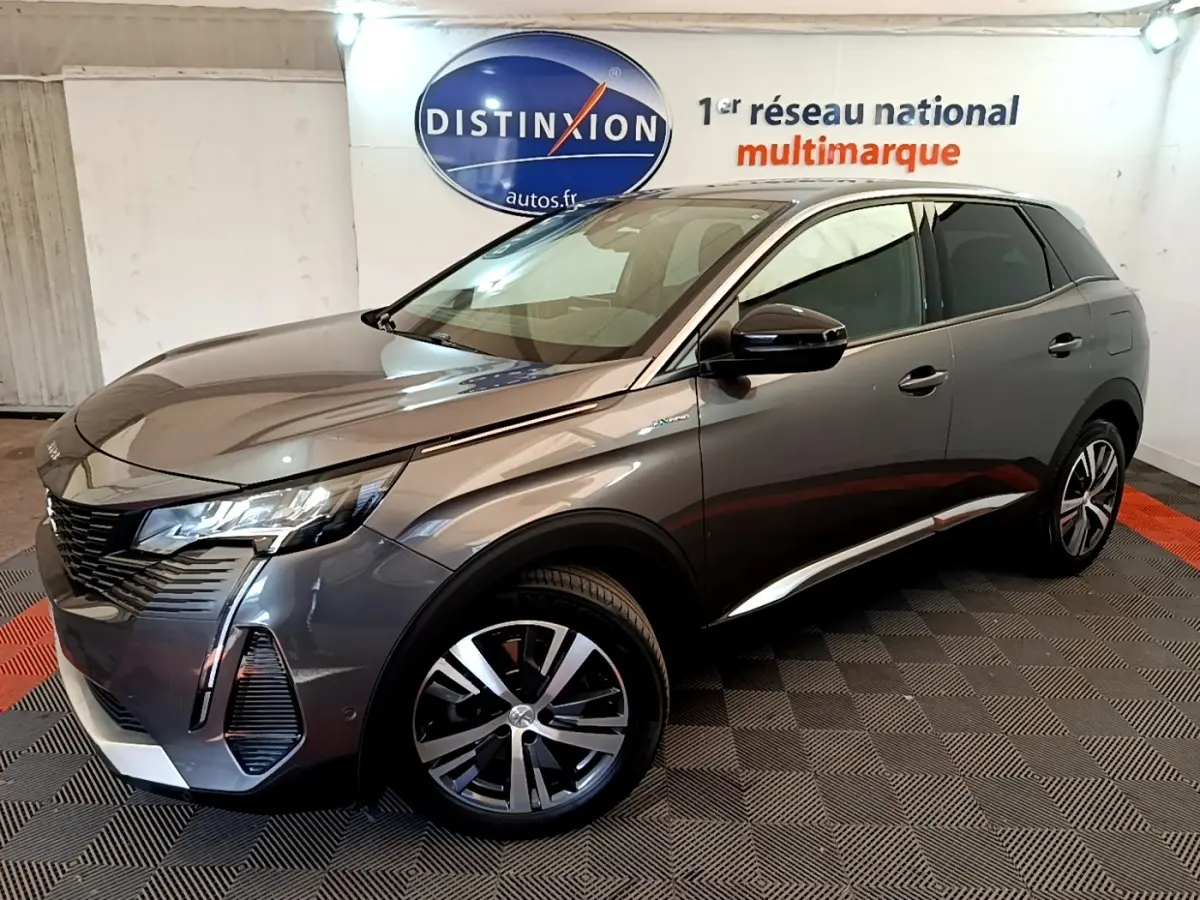 Peugeot 3008 gris foncé en 3/4 avant droit, avec jantes alliage et feux LED distinctifs, en intérieur showroom.