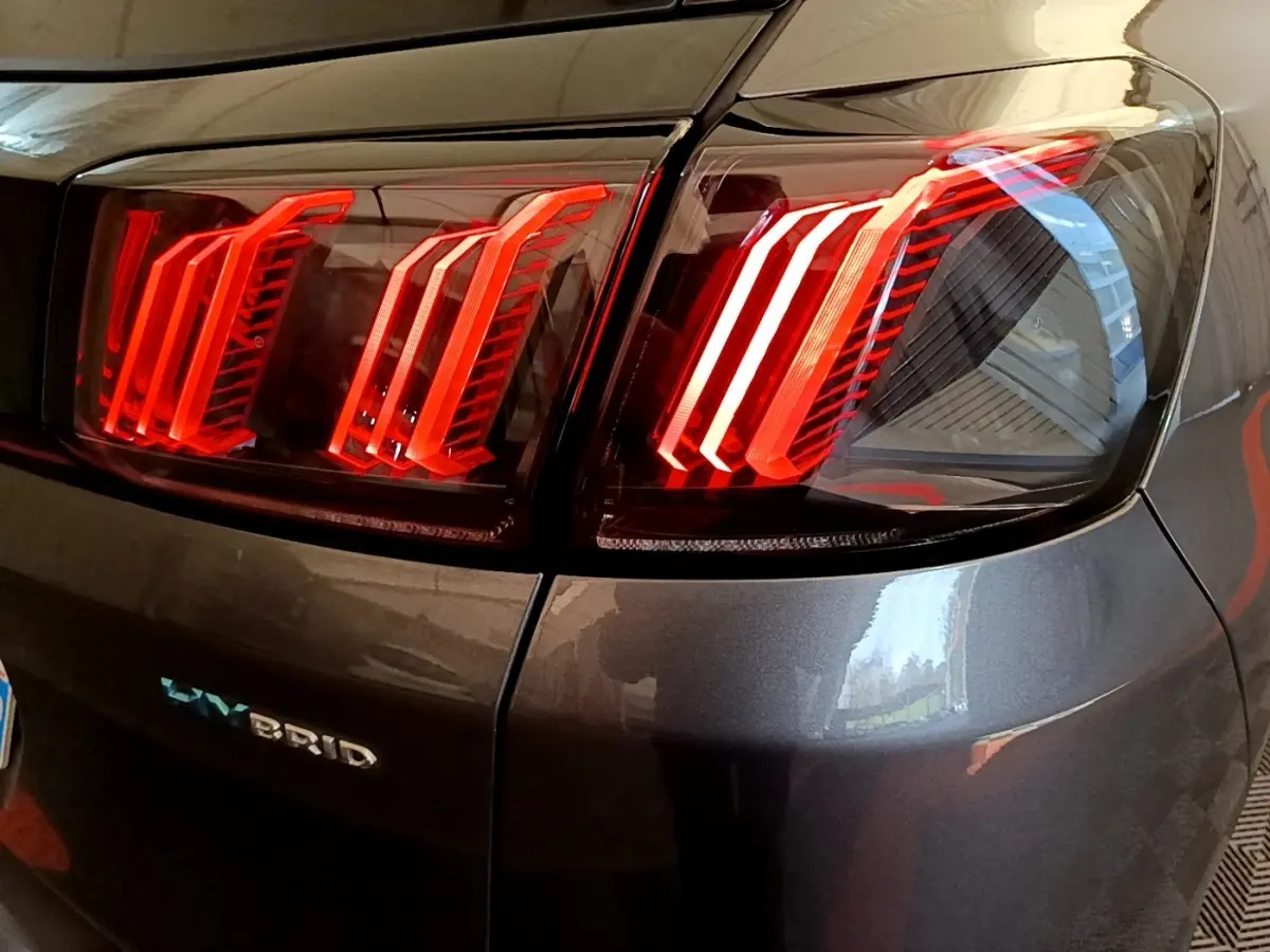 Gros plan sur les feux arrière allumés côté droit d’un Peugeot 3008 gris foncé hybride rechargeable.