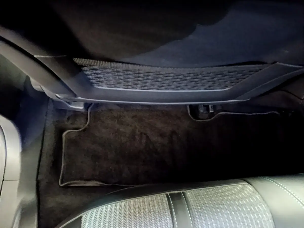 Vue intérieure côté passager avant du Peugeot 3008 gris foncé, montrant le tapis de sol et le dossier du siège.