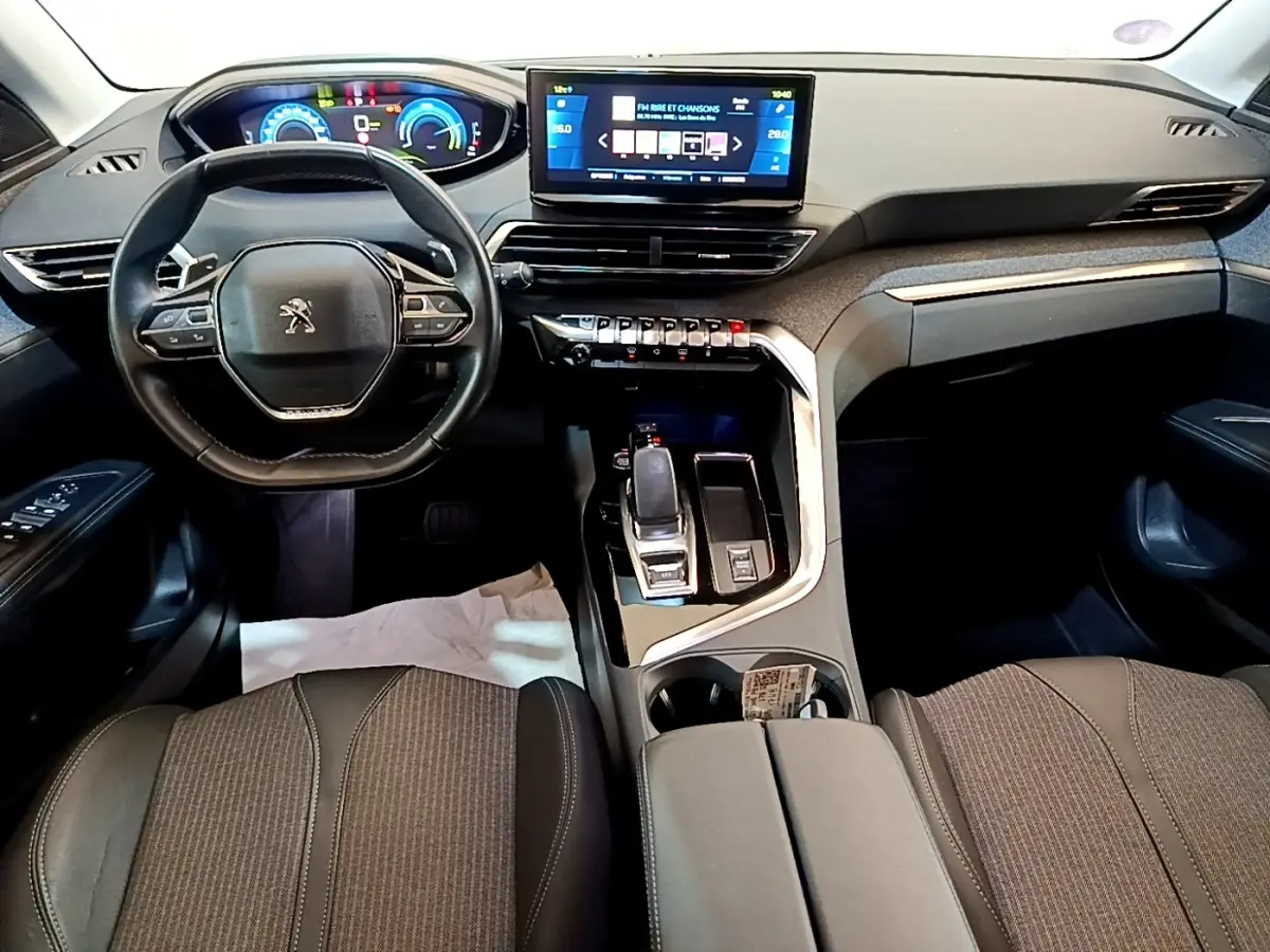 Intérieur Peugeot 3008 hybride 2022 vu de face, tableau de bord noir avec écran tactile central et volant compact cuir.