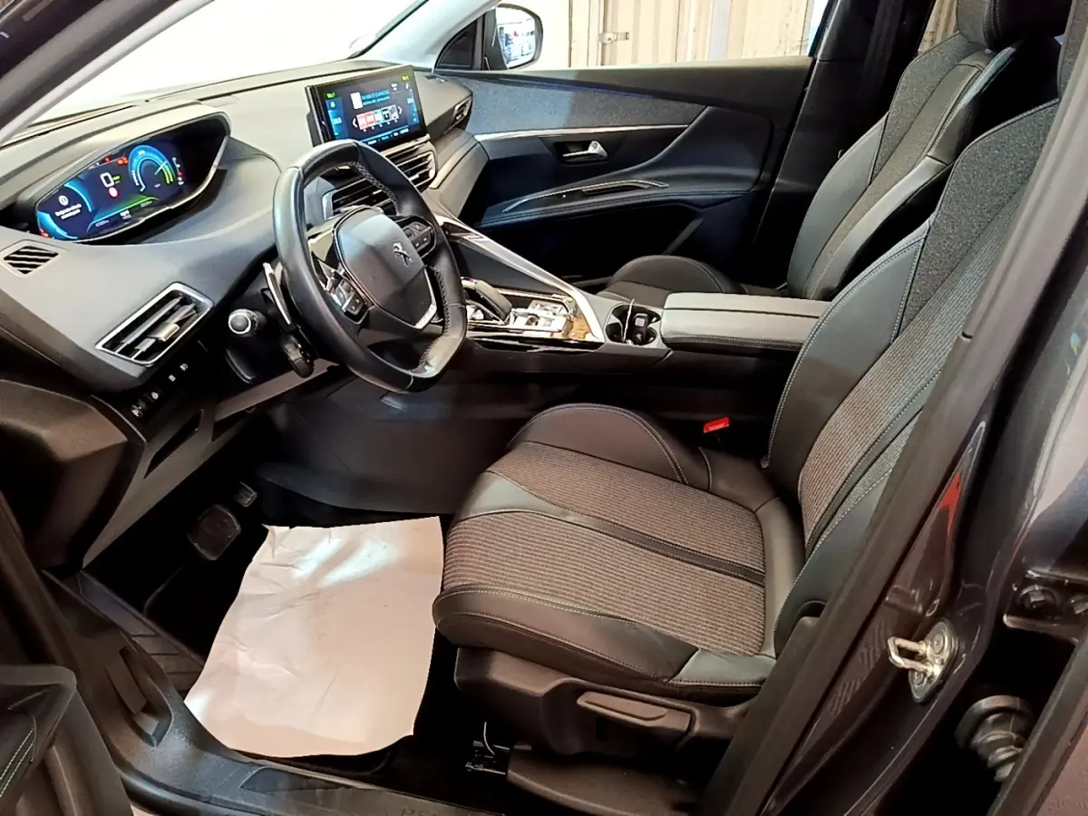 Vue intérieure côté conducteur du Peugeot 3008 gris foncé, avec tableau de bord digital et sièges tissu-cuir noirs.