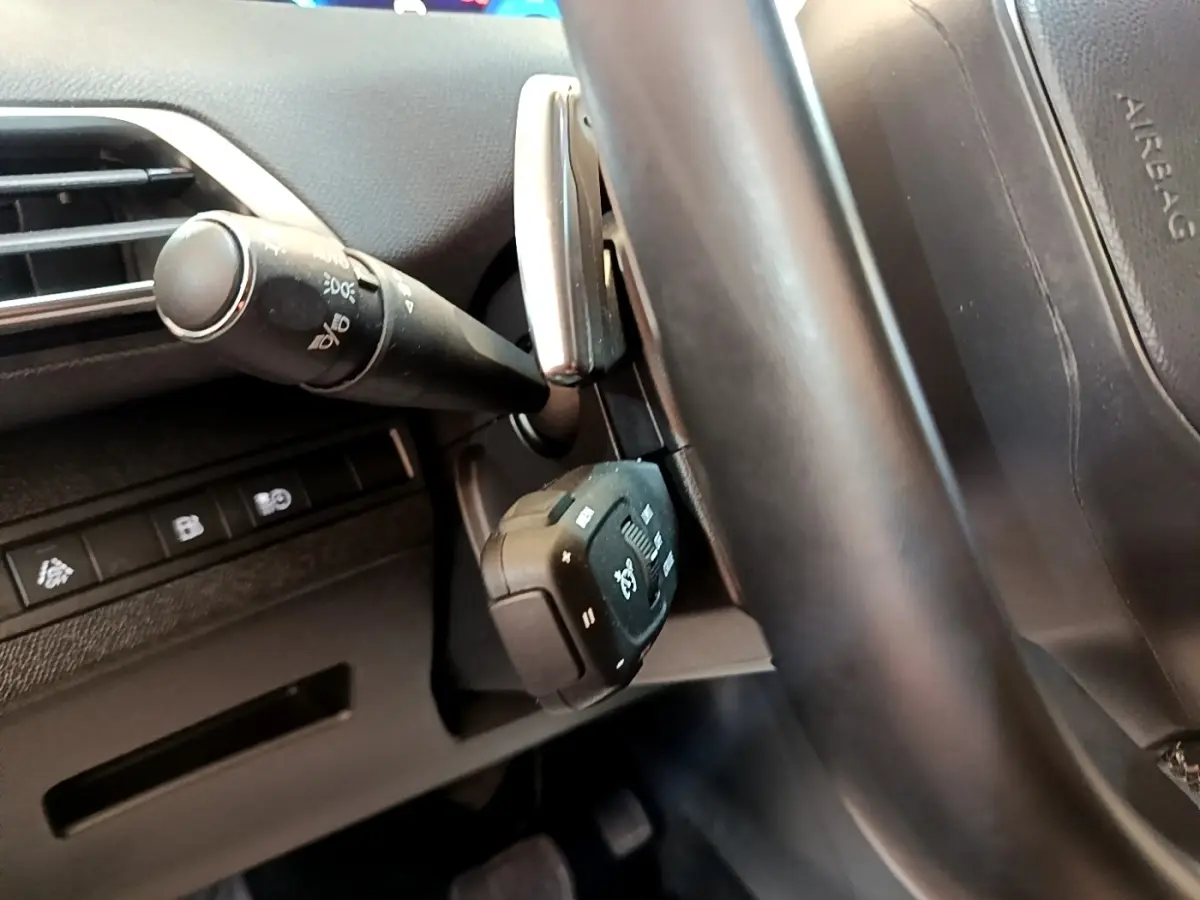 Gros plan sur les commandes au volant en cuir noir du Peugeot 3008 gris foncé, version hybride rechargeable 2022.