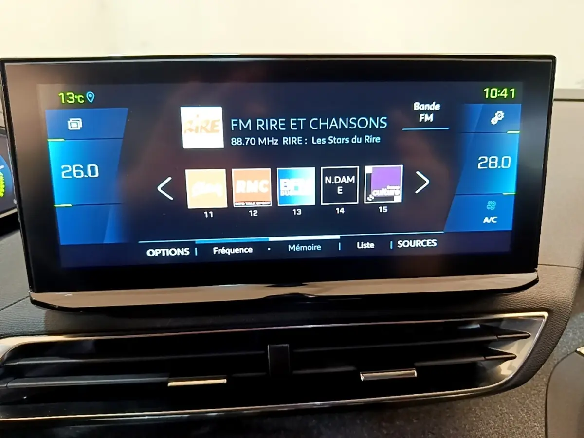 Écran tactile central du Peugeot 3008 gris foncé 2022 affichant la radio FM et la climatisation digitale.