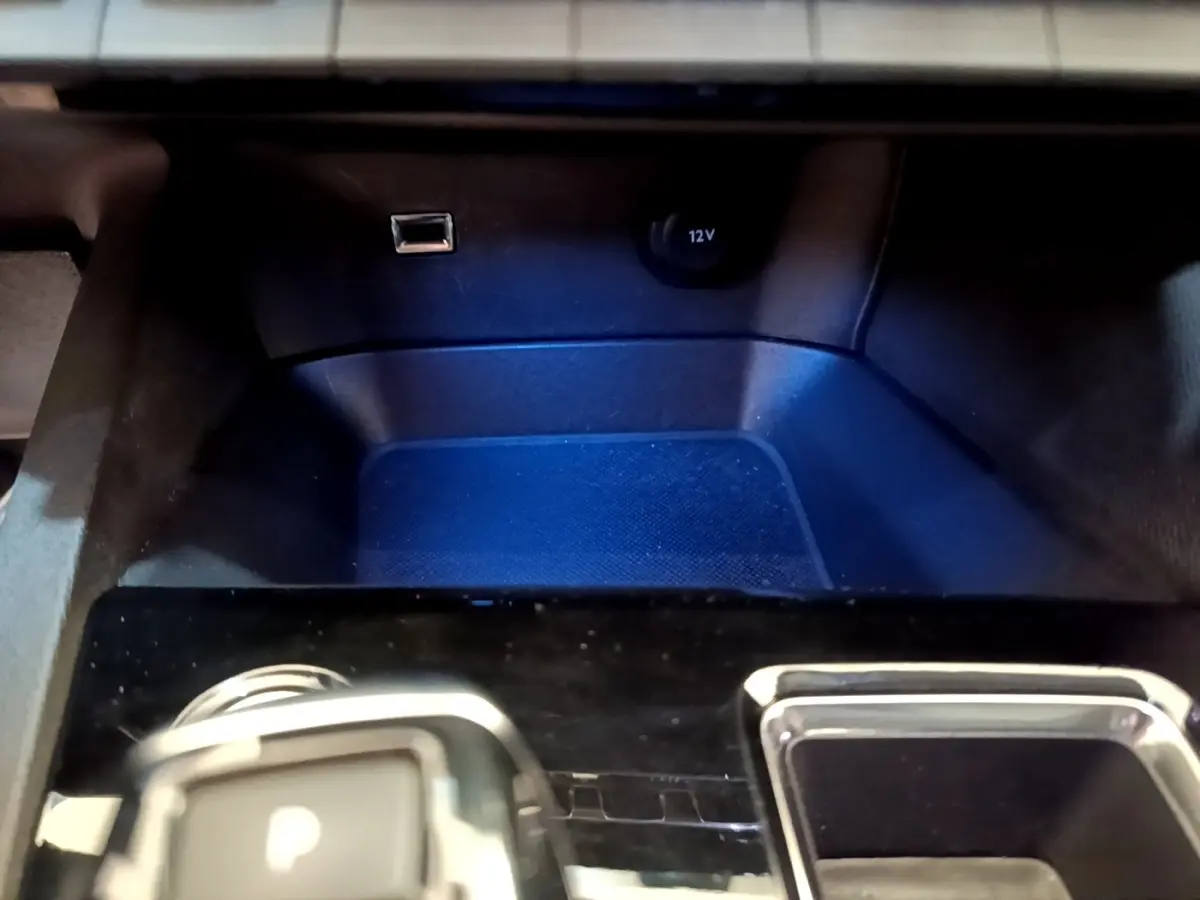 Gros plan sur la console centrale noire du Peugeot 3008 gris foncé, avec prise 12V et port USB visibles.