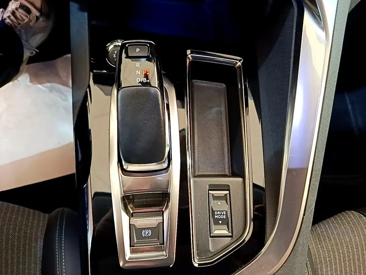 Gros plan sur la console centrale du Peugeot 3008 hybride gris foncé, avec levier de vitesses et bouton Drive Mode.
