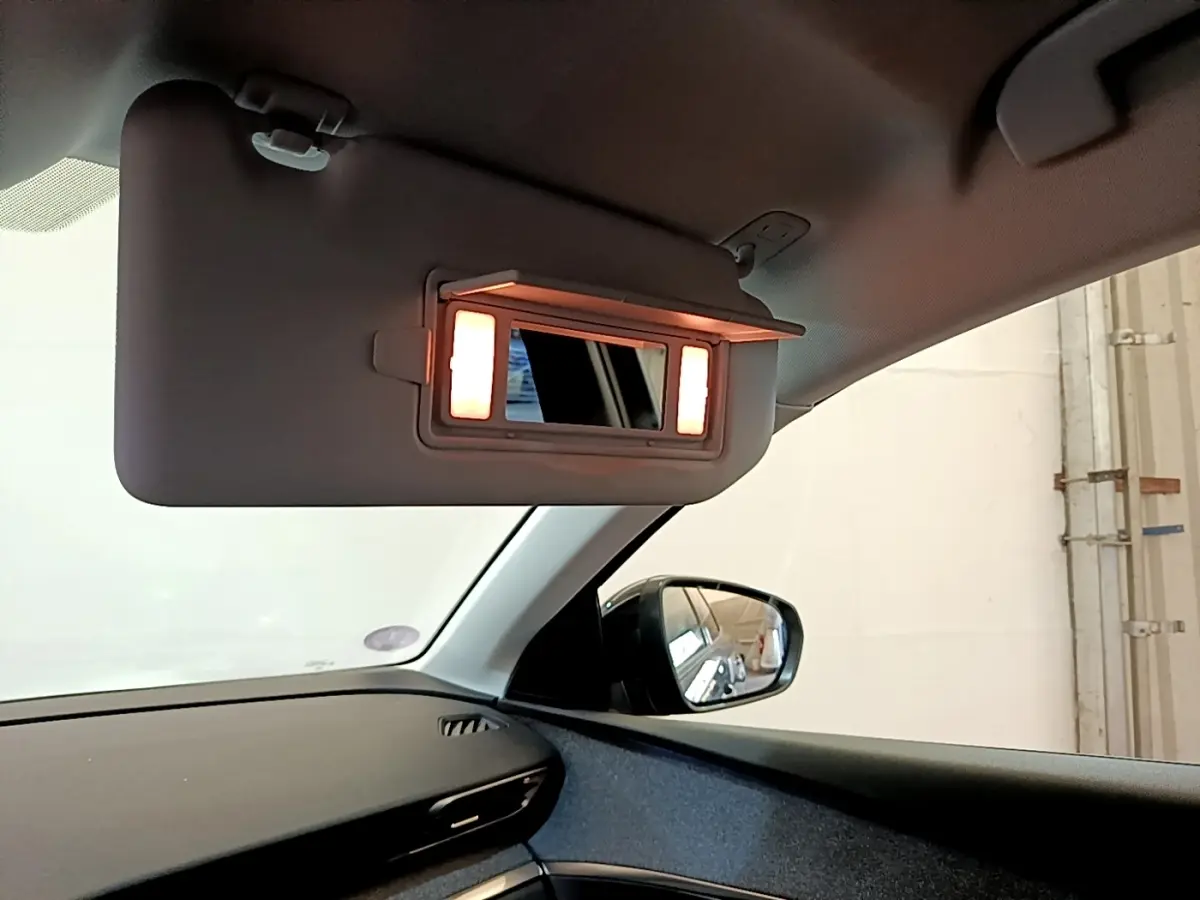Miroir de courtoisie éclairé sur pare-soleil côté conducteur dans l’habitacle d’un Peugeot 3008 gris foncé.