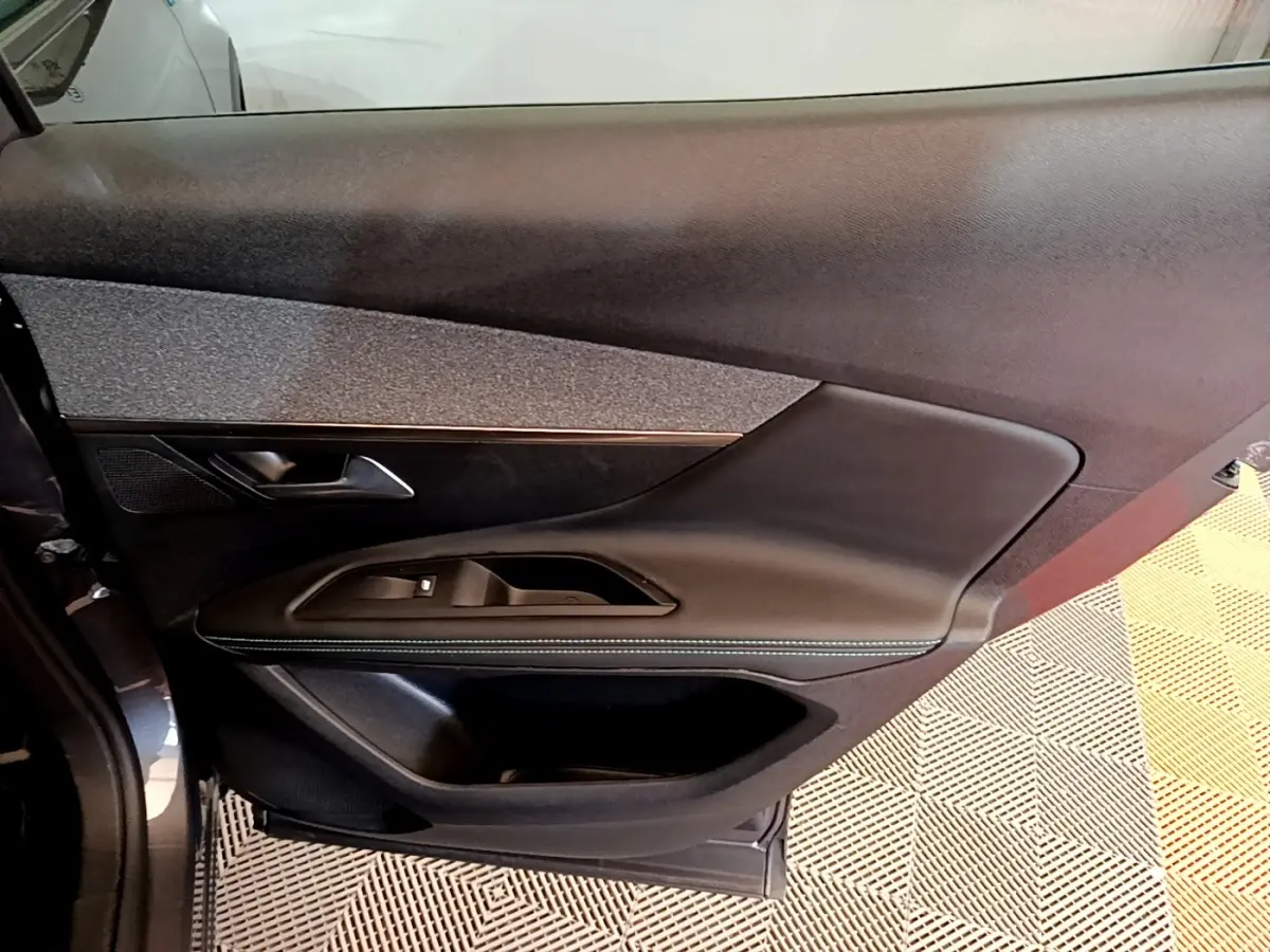 Gros plan sur la porte côté conducteur du Peugeot 3008 gris foncé, montrant les commandes de vitre et le revêtement noir texturé.
