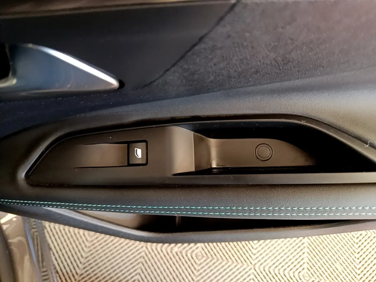 Gros plan sur la commande de lève-vitre côté conducteur avec surpiqûres bleues sur la garniture intérieure noire.