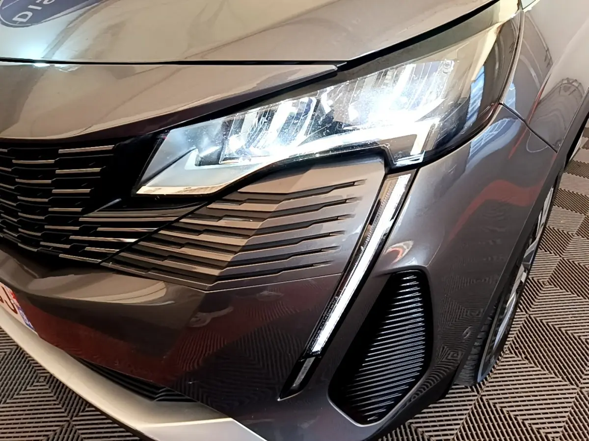 Gros plan sur l'avant droit gris foncé du Peugeot 3008 1.6 HYBRID 225 avec phares LED et calandre distinctive.