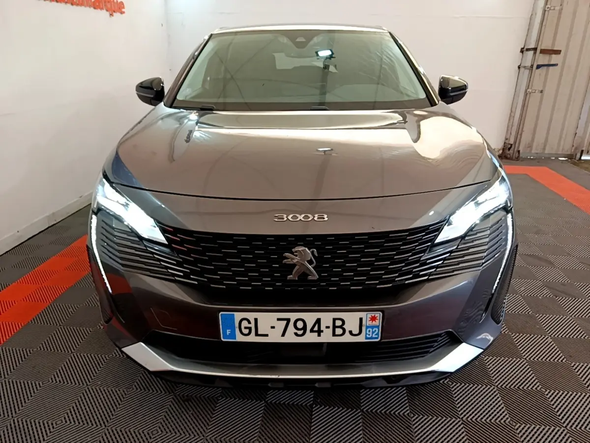 Vue avant d'un Peugeot 3008 gris foncé avec phares LED allumés et calandre noire distinctive.