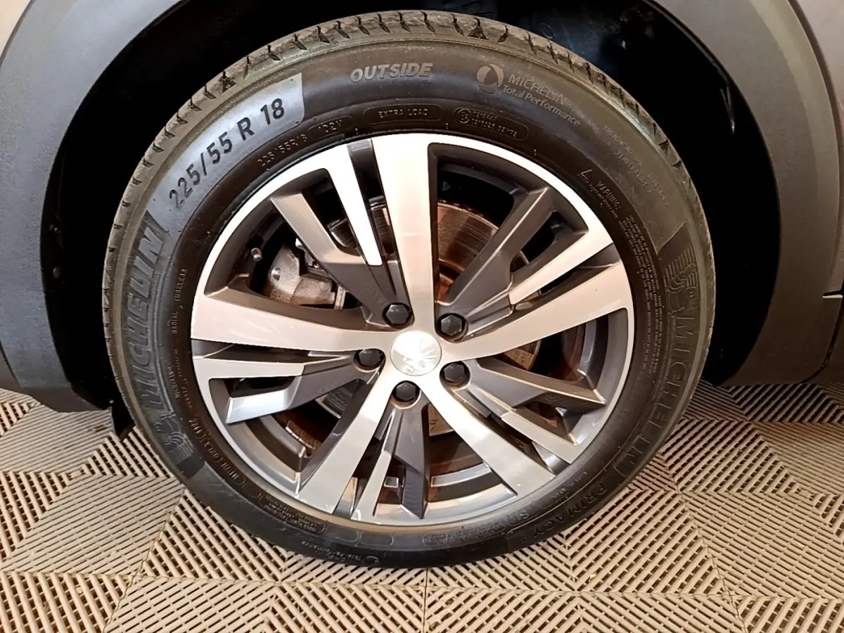 Gros plan sur la roue avant droite du Peugeot 3008 gris foncé, avec jante alliage moderne et pneu Michelin.