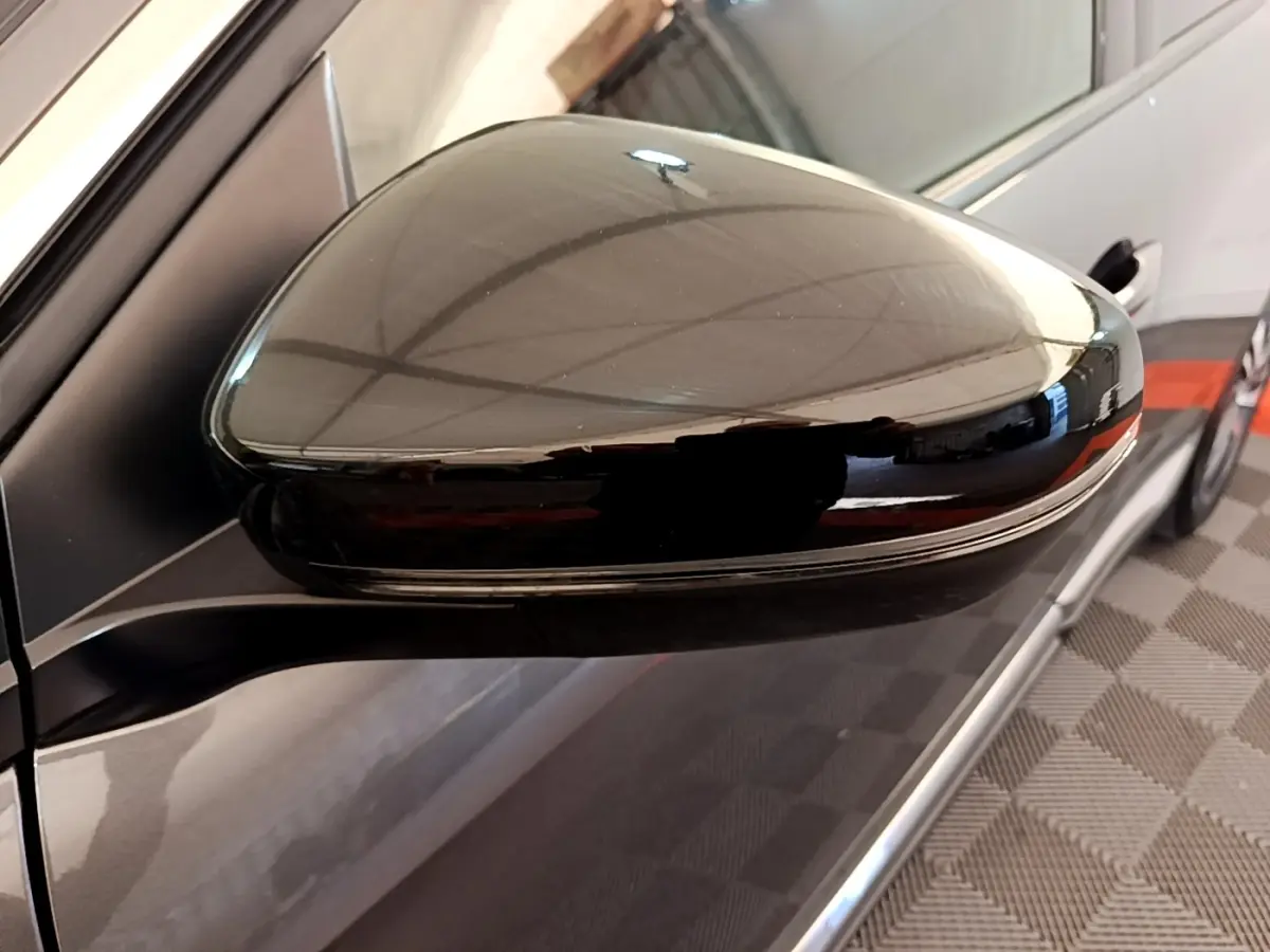 Rétroviseur droit noir brillant du Peugeot 3008 gris foncé, vue rapprochée avec reflet du plafond.
