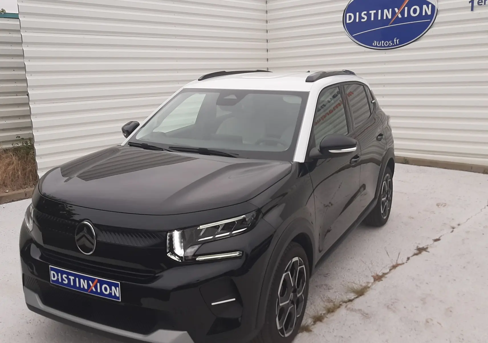 Citroën C3 1.2 Turbo 100ch Max noir perla avec toit blanc, vue 3/4 avant droit sur parking blanc.