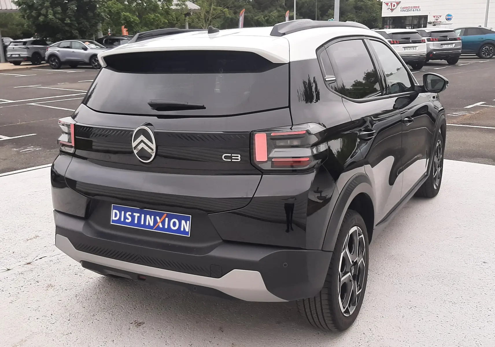 Vue 3/4 arrière droite d'une Citroën C3 2025 noir perla avec toit blanc, feux arrière LED et jantes bi-ton.