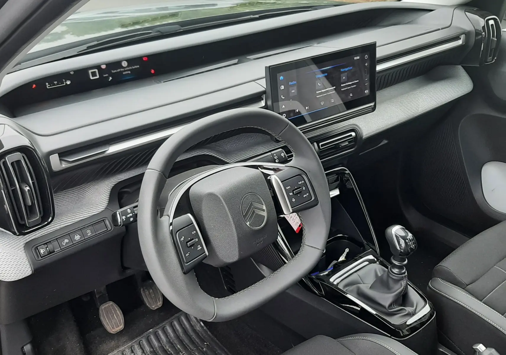 Vue intérieure côté conducteur de la Citroën C3 2025 avec volant multifonctions, écran tactile et levier de vitesses manuel.