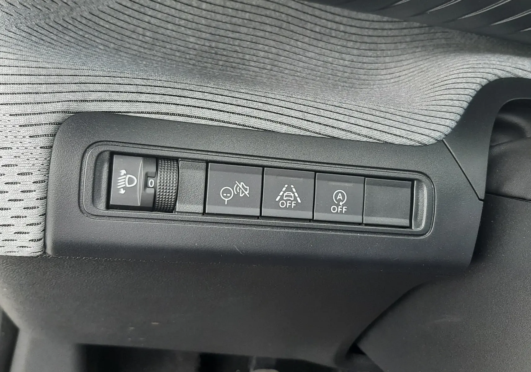 Gros plan sur les commandes de réglage des phares et aides à la conduite de la Citroën C3 1.2 Turbo 2025, intérieur noir.