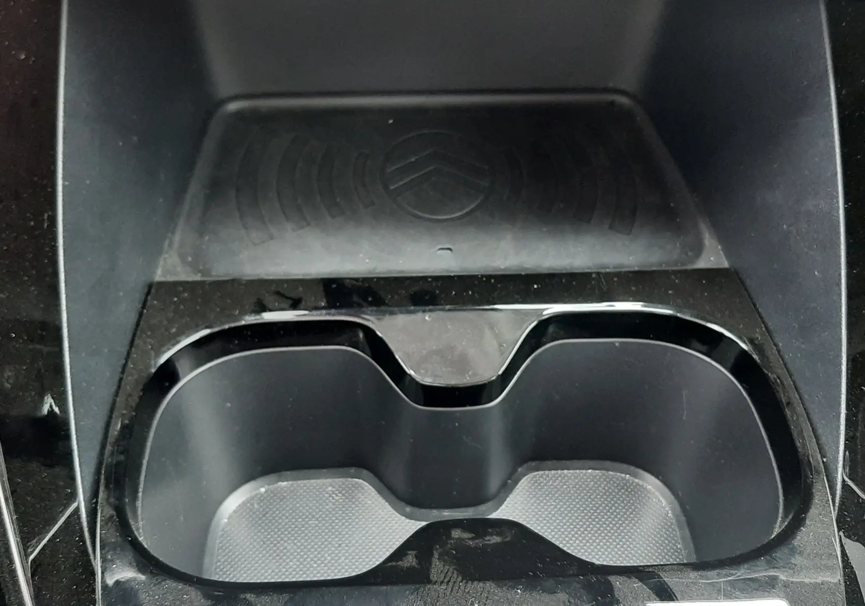 Vue rapprochée de la console centrale noire de la Citroën C3 2025, avec porte-gobelets et surface antidérapante au logo Citroën.