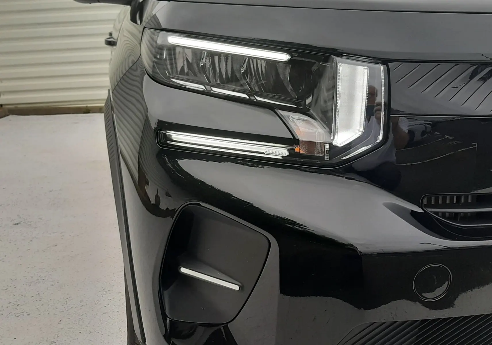 Gros plan sur l'avant gauche noir perla avec toit blanc de la Citroën C3 2025, mettant en valeur les phares LED distinctifs.