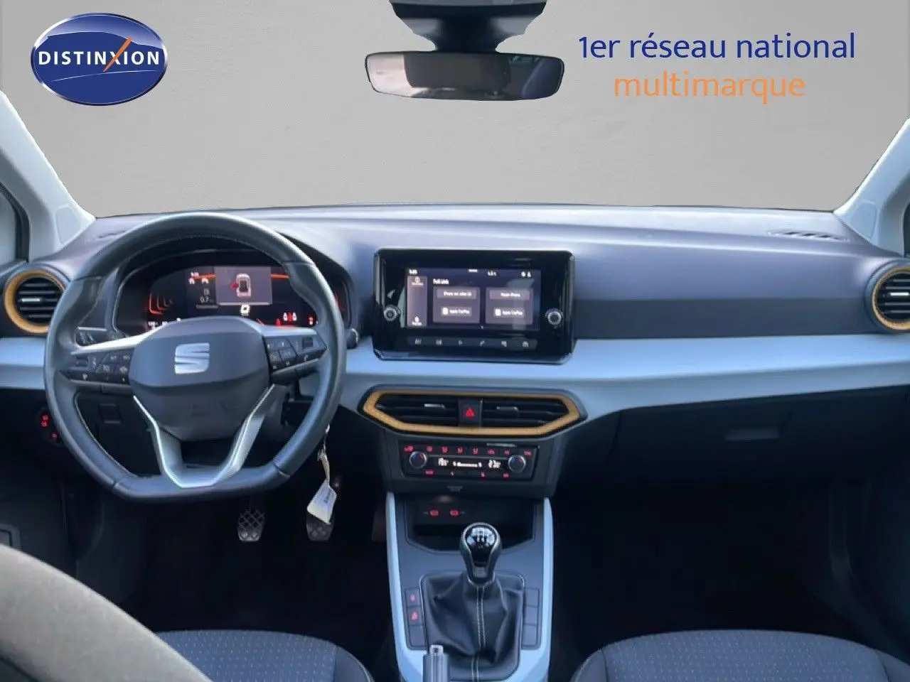 Vue intérieure frontale du tableau de bord du SEAT Arona blanc avec toit gris, volant multifonction et écran tactile central.