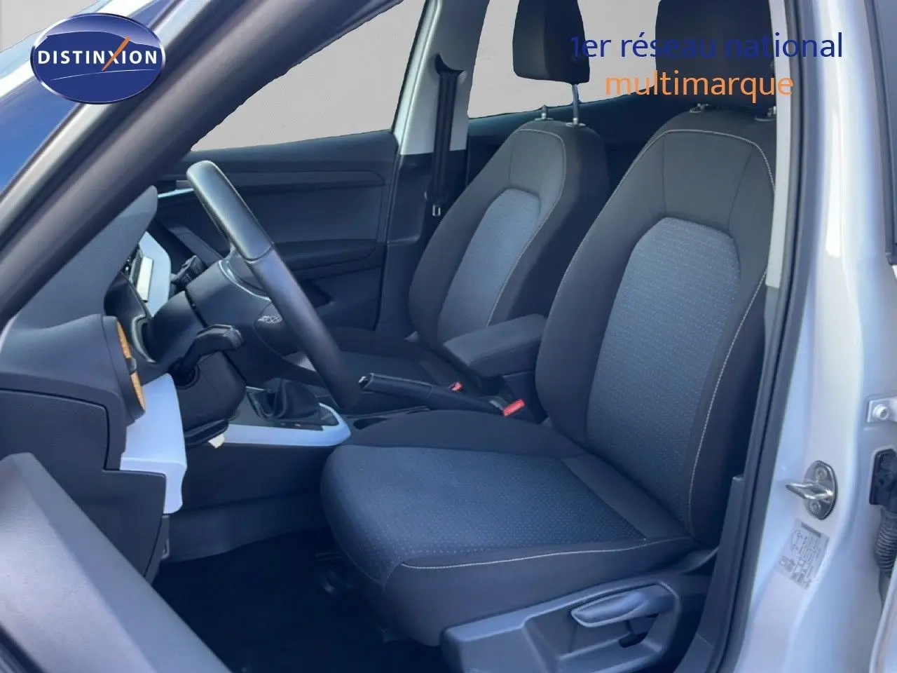 Vue intérieure côté conducteur du SEAT Arona blanc avec toit gris, sièges tissu gris foncé et volant multifonction.