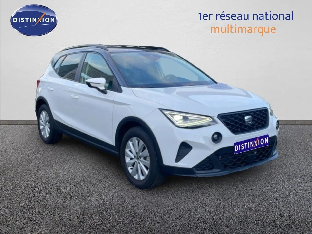 SEAT Arona blanc avec toit gris, vue 3/4 avant droit, feux allumés et calandre noire distinctive.