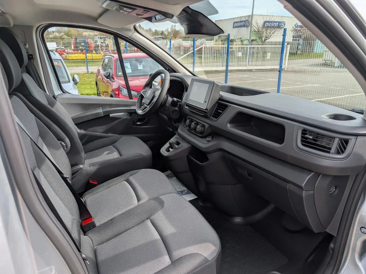 Vue intérieure côté conducteur du Renault Trafic Fourgon gris, mettant en valeur la cabine approfondie et l'écran tactile central.