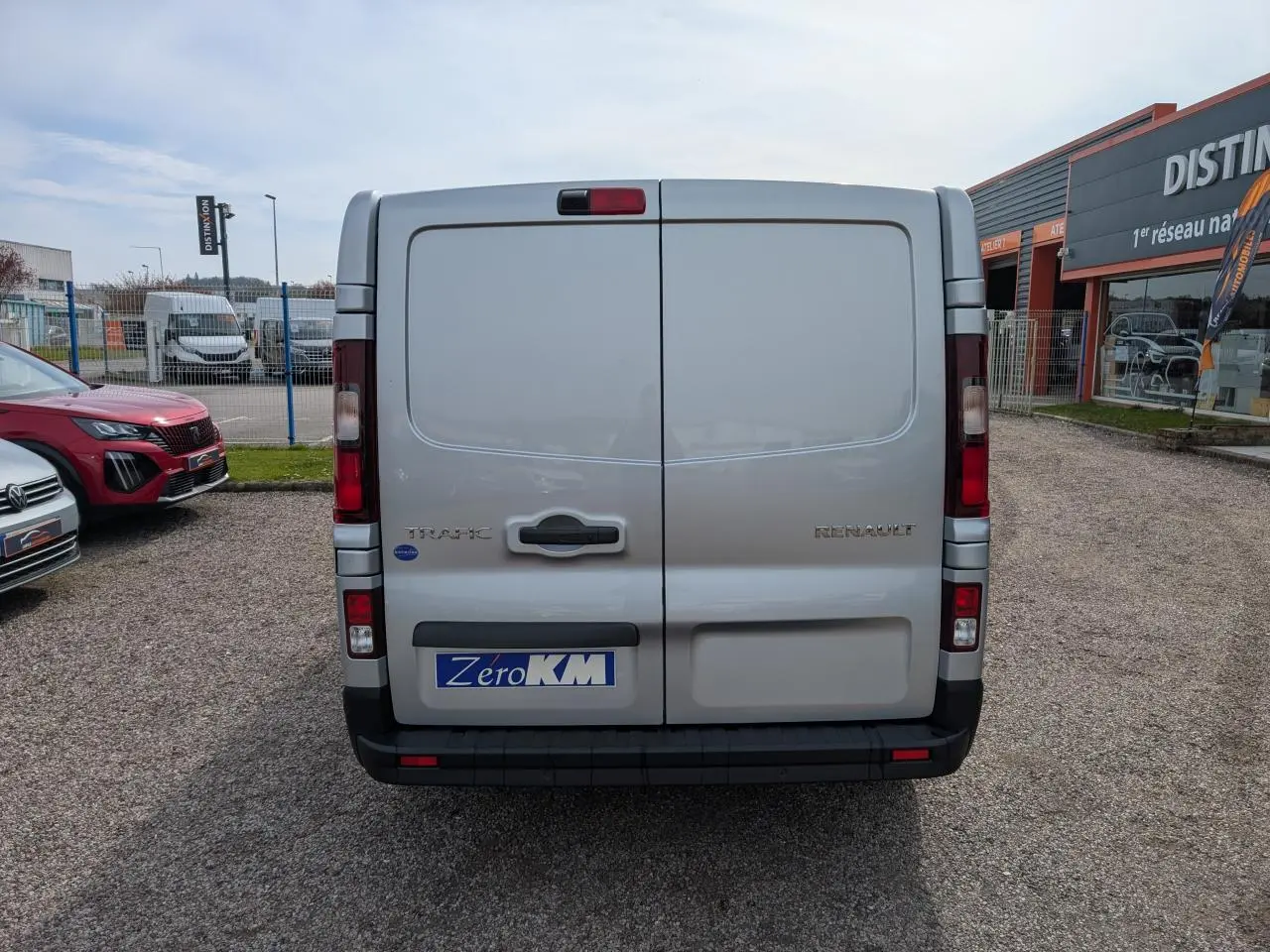 Vue arrière d'un Renault Trafic Fourgon gris avec portes battantes et feux arrière intégrés à la carrosserie.