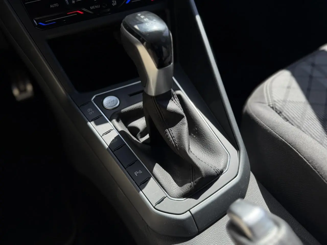 Gros plan sur la console centrale et levier de vitesse automatique du Volkswagen Taigo TSI 116 DSG R-Line, intérieur gris.